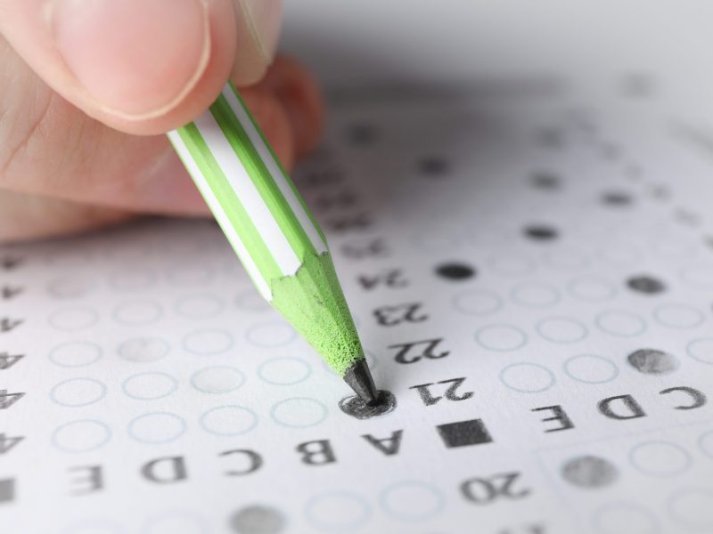 Student fills answers test sheet, close up